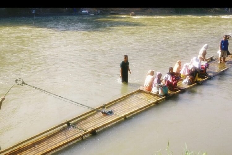 Warga saat menaiki rakit menyebrang kali Cibuni